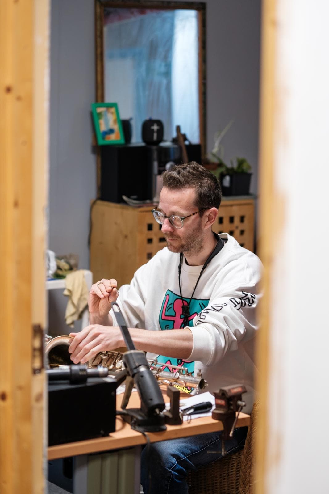 A shot from outside the door looking in, Joe inspects a saxophone