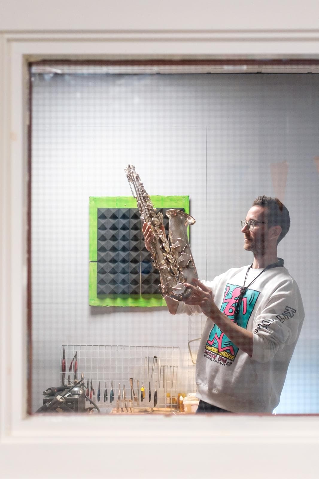 A shot through a window, Joe holds up a finished repair