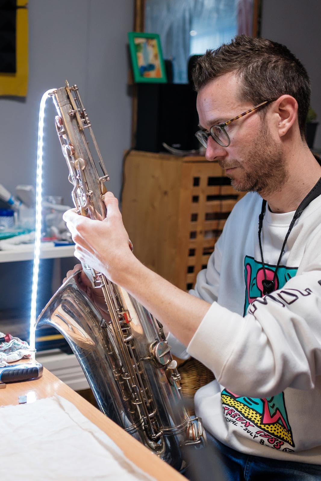 Joe strings lights through a broken saxophone to inspect the damage